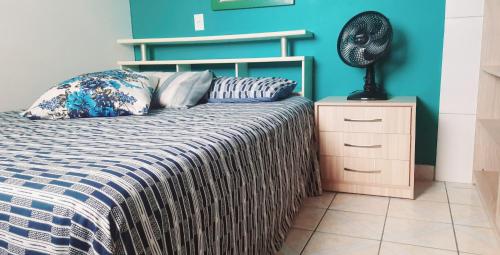 皮涅拉Pousada Mar Aberto Pinheira的一间卧室配有一张床,床头柜上配有风扇
