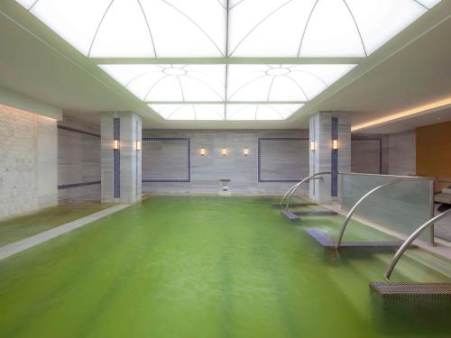 伯萨Mövenpick Hotel & Thermal Spa Bursa的大型客房,设有绿色的游泳池
