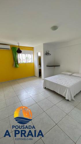 帕纳米林Pousada A Praia的一间卧室设有一张床和黄色的墙壁