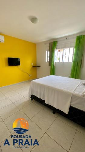 帕纳米林Pousada A Praia的一间卧室设有一张黄色墙壁的大床