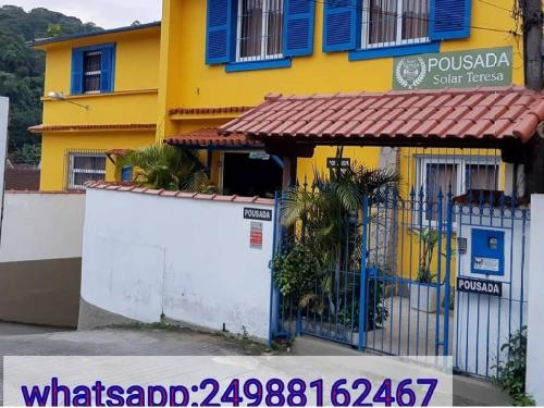 彼得罗波利斯Pousada Solar Teresa的黄色和蓝色的建筑,设有大门