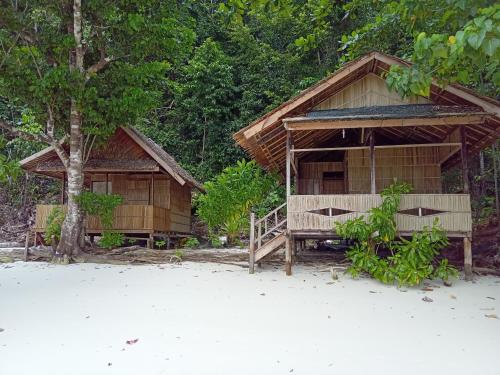 Yennanas BesirYenrou Homestay的海滩上一些树旁的房子