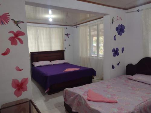 波帕扬hostal Sueño Paraiso- Observatorio astronómico的卧室配有两张床,墙上挂着鲜花。