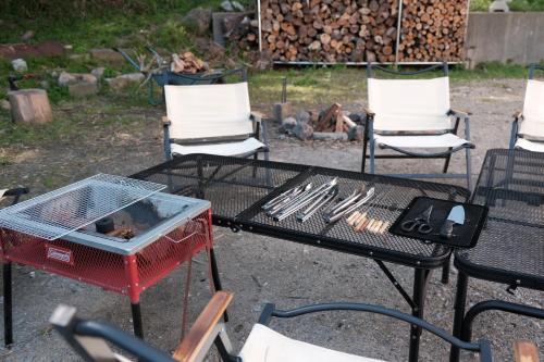 一軒家貸切 ARUYOguesthouse BBQと焚き火ができる宿的一张带烧烤架和椅子的桌子以及一个壁炉