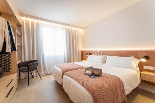 马翁ARTIEM Apartamentos的酒店客房,配有两张床和椅子