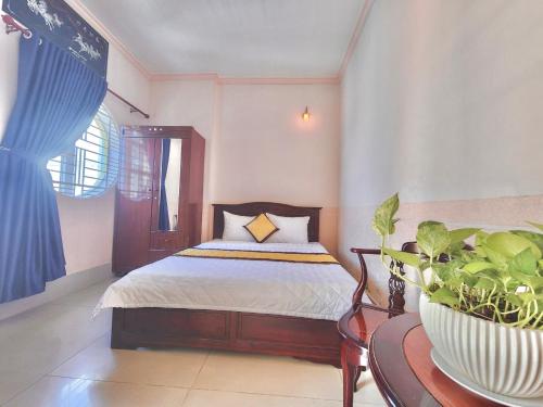 芹苴NAMA HOTEL - Ninh Kieu Center的一间卧室配有一张床和一张植物桌子