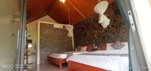 枚州县Mai Chau Hillside Homestay的一间卧室设有两张床和砖墙