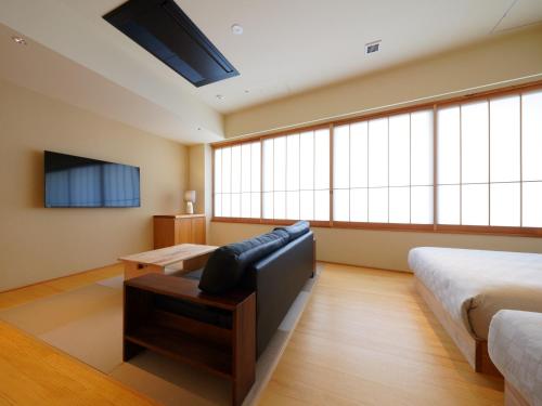 别府MURE Beppu的一间带两张床、一张沙发和一台电视的卧室