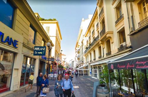 尼斯Haliviera - Golden Square, 1min from beach的一群人沿着街道走着,街道上有许多建筑