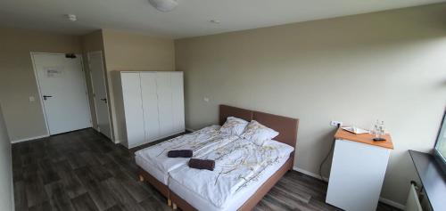 SiebengewaldHiway Motel的一间卧室配有一张铺有木地板的白色床单。