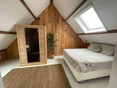 阿讷默伊登B & B 'Droom in de polder de Suite met prive sauna的阁楼卧室设有床和窗户。