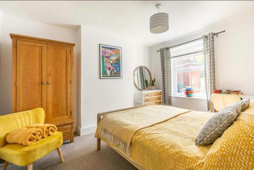 福克斯通Bradstone Garden Retreat的一间卧室配有一张床和一张黄色椅子