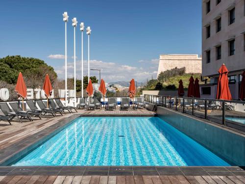 马赛New Hotel of Marseille - Vieux Port的一座大楼内的游泳池,配有椅子和遮阳伞