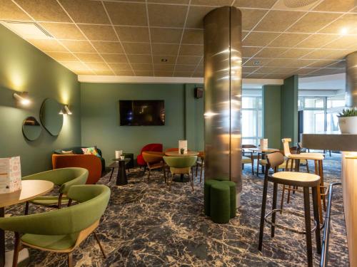 布尔日布尔吉诺富特酒店的餐厅拥有绿色的墙壁和桌椅