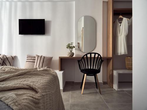 拉加纳斯Cassiopeia Rooms & Suites的一间卧室配有一张床、一把椅子和镜子