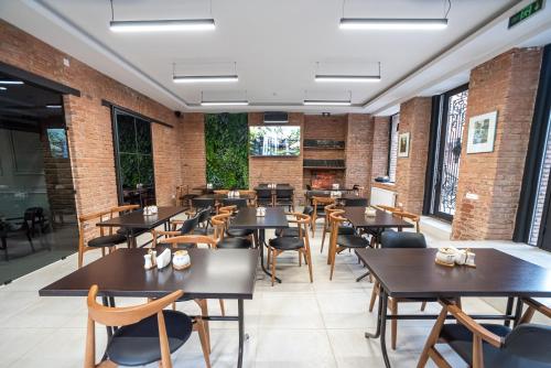 第比利斯第比利斯酒店的餐厅设有木桌、椅子和砖墙