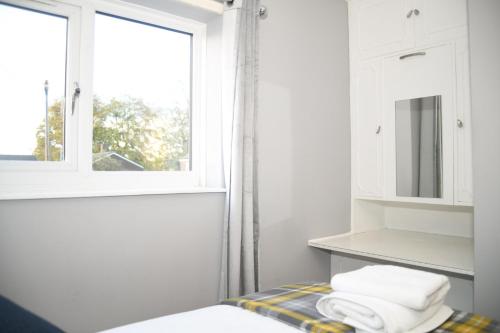 沃尔索尔2ndHomeStays -Willenhall-Charming 3-Bedroom Home的白色的浴室设有窗户,床上配有毛巾