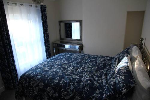 康威Charming Mid Terrace Cottage的一间卧室配有一张带蓝色床罩的床和窗户。