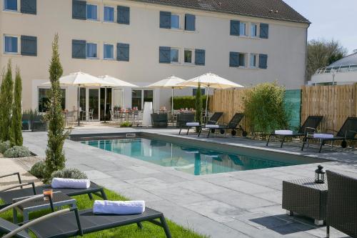 基扬古尔凡尔赛心愿贝斯特韦斯特酒店的一座带桌椅的游泳池位于酒店大楼旁