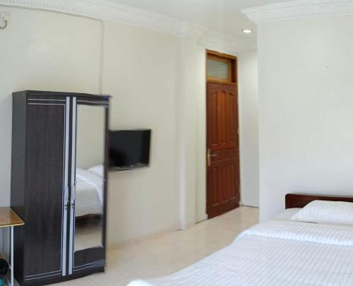 巴东Flamboyan House的一间卧室设有两张床,墙上配有电视。