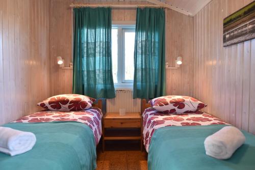 布伦迪欧斯Laxás Cottage的客房设有两张床和一个带绿色窗帘的窗户。