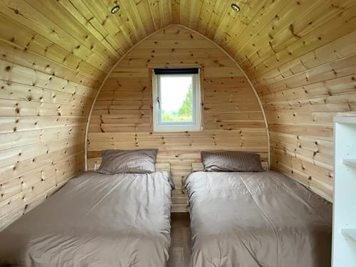丹比F&H Camping的小木屋内的两张床,设有窗户