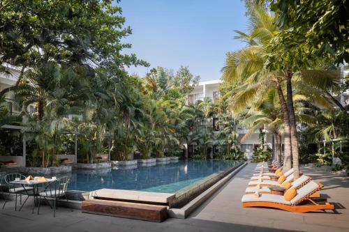 金边Plantation Urban Resort & Spa的度假村的游泳池,设有躺椅和棕榈树