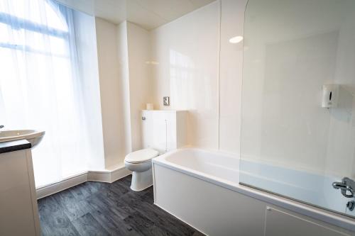 巴克斯顿巴克斯顿皇宫酒店及Spa的浴室配有白色浴缸和卫生间。