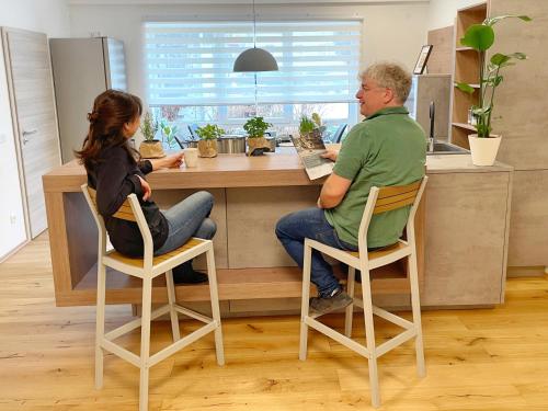 施塔特韦伦Edle neue Ferienwohnungen in der Nähe der Bastei的坐在厨房柜台上的男女