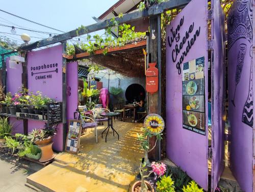 清迈帕普度旅舍的紫色的建筑,配有桌椅和植物