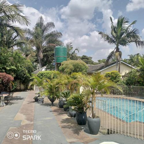 哈拉雷Guesthouse with green garden and pool - 2102的一座棕榈树和围栏的游泳池