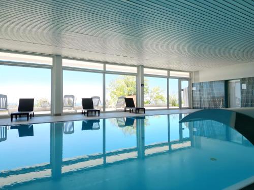 弗赖翁格耶斯堡假日公园酒店的一座带椅子和窗户的建筑中的游泳池