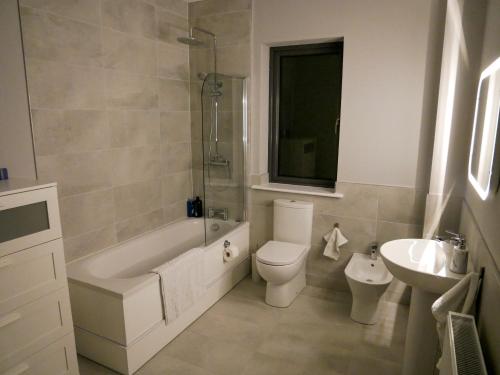 威克洛Entire Modern Home with seaview and parking的带浴缸、卫生间和盥洗盆的浴室