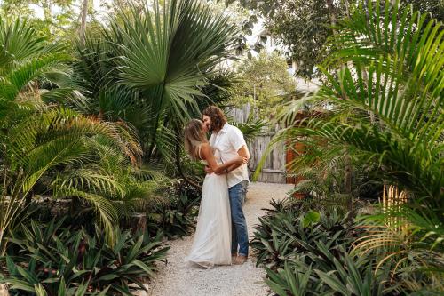 图卢姆Nahouse Jungle Lodges的花园里的一名新娘和新郎亲吻