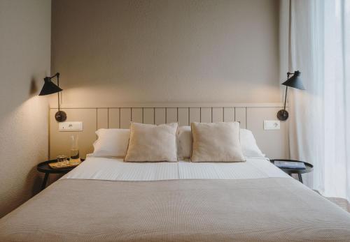 卡达克斯雅内佩提特酒店的卧室配有一张带白色床单和枕头的大床。