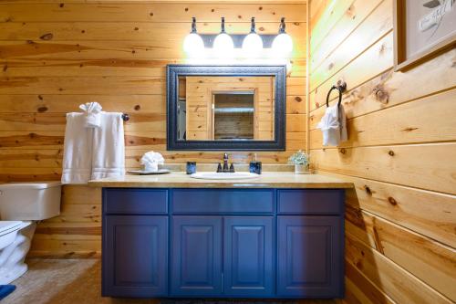 布罗肯鲍Hickory Bear - Cabin surrounded by pines, Sleeps 10, Hot Tub, Fire Pit, Arcade, Foosball Table & Deck Slide的浴室设有蓝色水槽和镜子