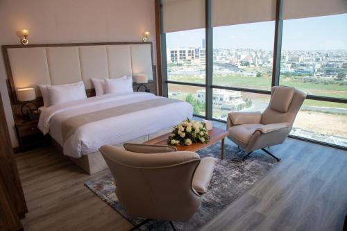 安曼Jeddah Homes Boutique Hotel的酒店客房,配有一张床和两把椅子