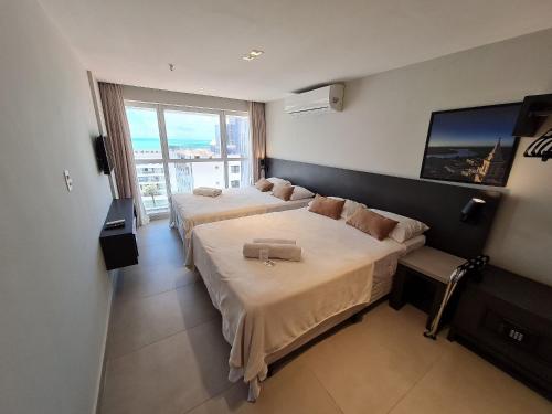 若昂佩索阿Lindos Flats Studios no Qualité的酒店客房设有两张床和大窗户。
