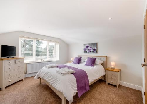 BrisleyLillie Cottage的一间卧室配有一张带紫色枕头的大床