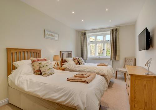 ElsingMill Cottage的一间卧室配有两张床、一张桌子和一台电视。