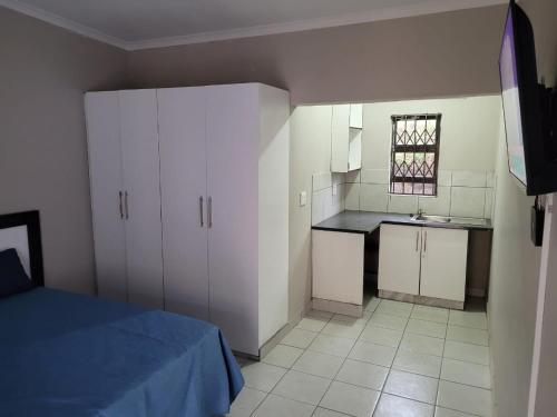 恩潘盖尼Mavundla lifestyle lodge的一间设有一张床的客房和一间带白色橱柜的厨房
