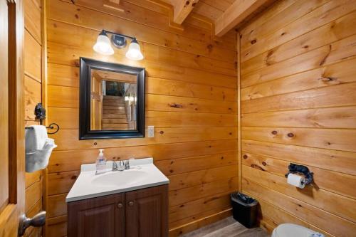 赛维尔维尔2-Bedroom Cabin with 2 Master Suites, Loft, Half-Bath and hot tub in a Serene Resort Setting的浴室设有木墙、水槽和镜子
