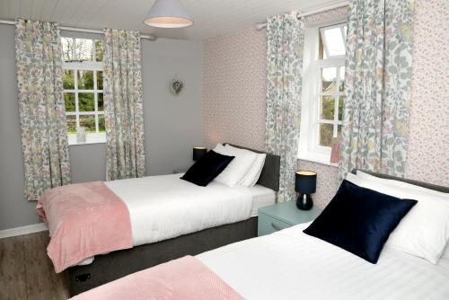 CloverhillCloverhill Gate Lodge的配有窗户和窗帘的客房内的两张床