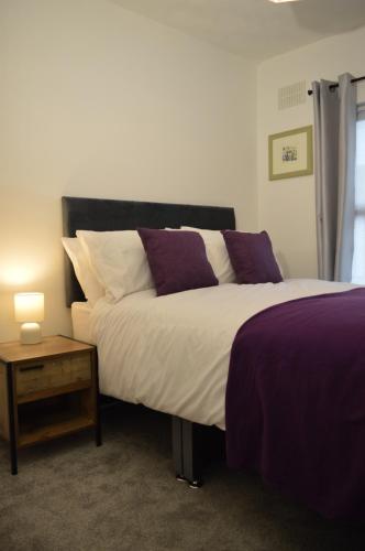 利物浦Library House的一间卧室配有一张大床,提供紫色和白色枕头