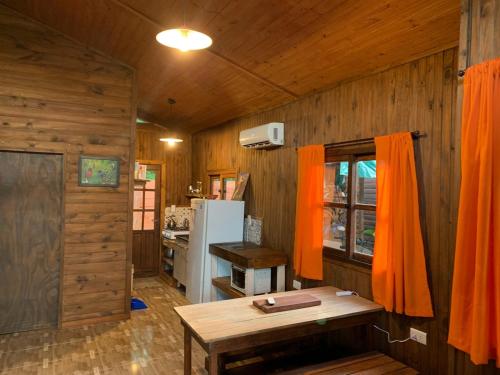 伊瓜苏港Los Bananos - Big Wood Cabin的厨房设有木墙、桌子和冰箱。