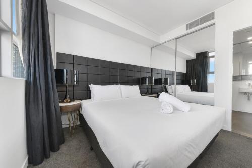 悉尼Broad Land Premium Apartments Chatswood Sydney的一间卧室配有两张白色的床和镜子