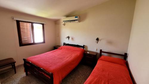 特尔马斯德里奥翁多Departamento的一间卧室设有两张带红色床单的床和窗户。