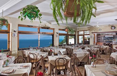 卡普里大乔治酒店的餐厅设有白色的桌椅和窗户。