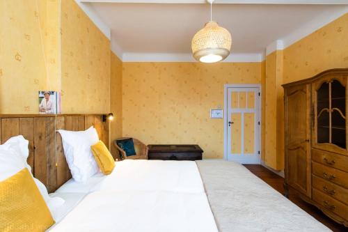巴斯托涅Maison spacieuse unifamiliale. Gîte La Clochette的卧室设有一张白色大床和黄色墙壁