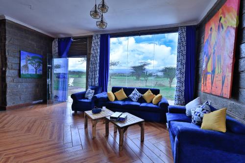 安博塞利Amboseli Cultural Camping的客厅设有蓝色的沙发和大窗户